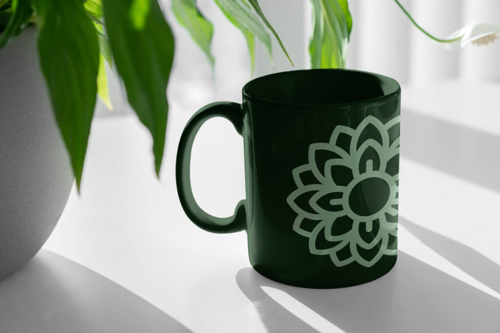 A green coffee mug featuring a decorative flower design.